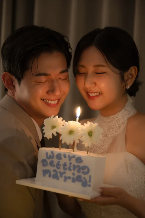 데이지꽃과 촛불이 있는 케이크 앞에서 함께 웃는 두 사람